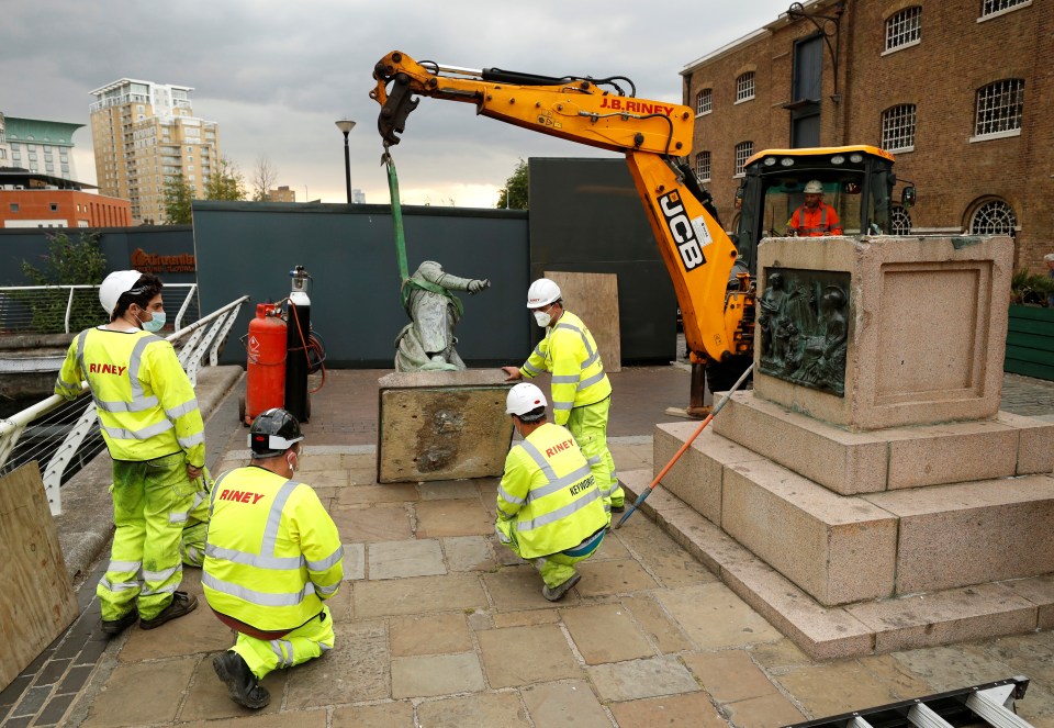  Workers can be seen removing the statue from its plinth after a similar one was toppled by protesters in Bristol over the weekend