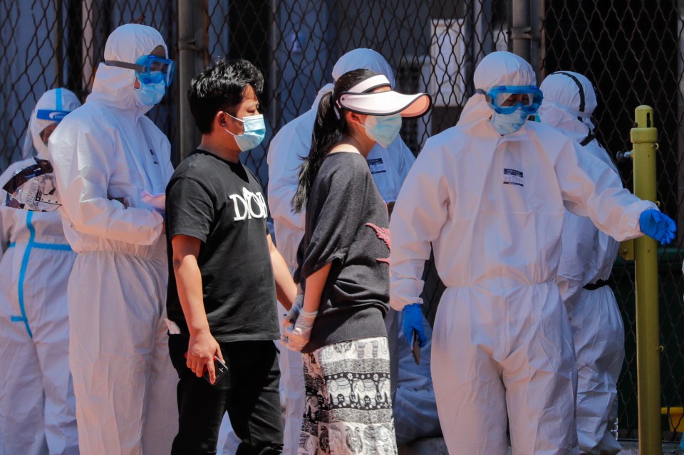  Officials in protective suits direct residents for coronavirus testing as authorities race to halt the spread