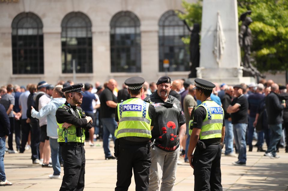  Police talk with a man as protesters gather by the Cenotaph in Victoria Gardens, Leeds