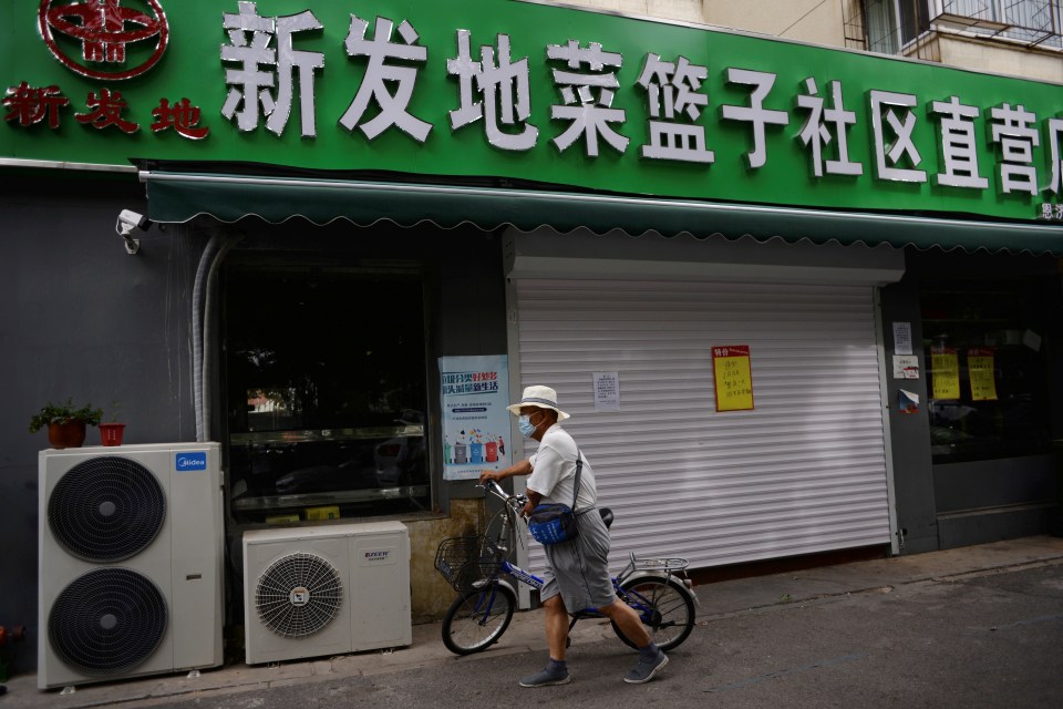 A man walks past a closed convenience store that sells produce from the Xinfadi wholesale market