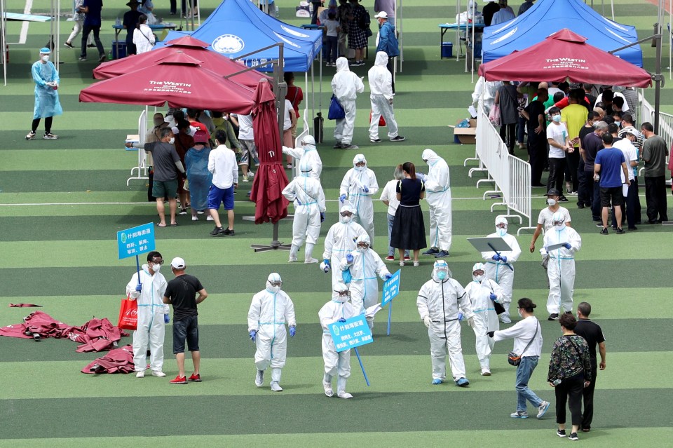 Medical workers in protective suits inside a sports centre carry out nucleic acid tests, following a rise in coronavirus cases in Beijing, China