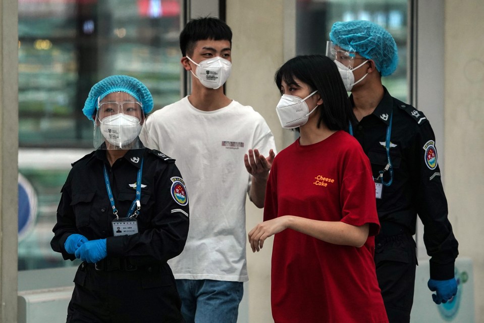 Airport security staff and passengers wearing protective face masks at terminal 3 of Beijing Capital International Airport