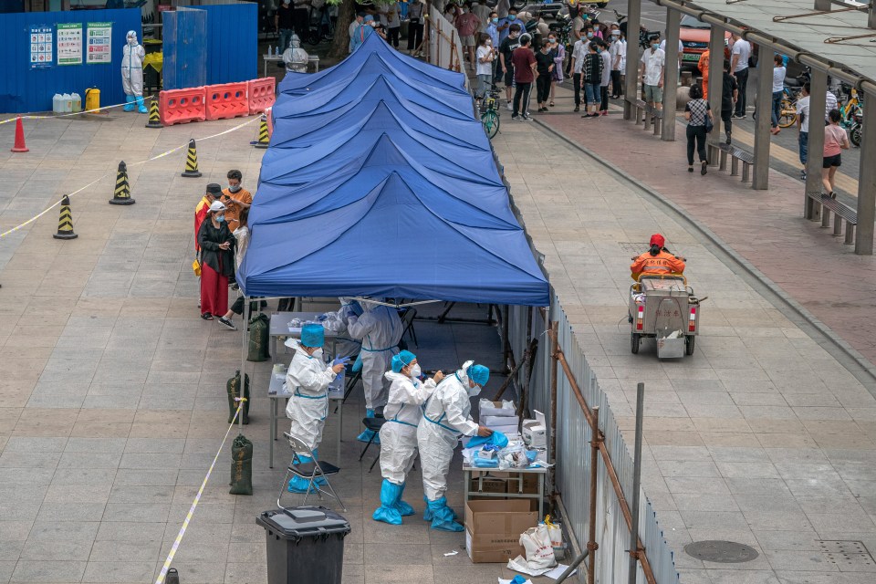 Medical workers wearing full protective suits prepare to test people for Covid-19