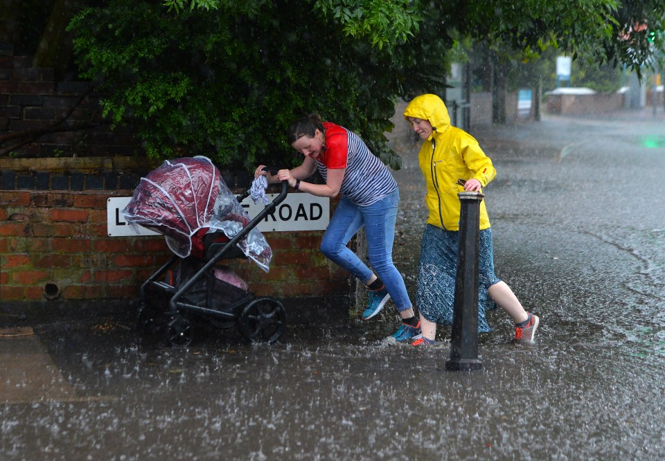  A mum pushes her buggy through the heavy rain in Leicester