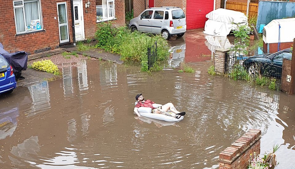  A savvy homeowner has been spotted floating on a lilo in a flooded street in Derby