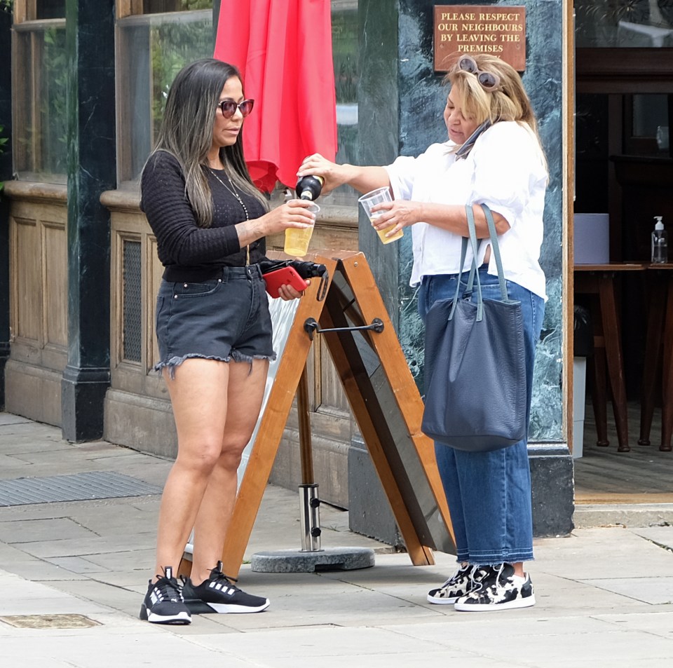 Two pals meet up for a pint outside a London pub