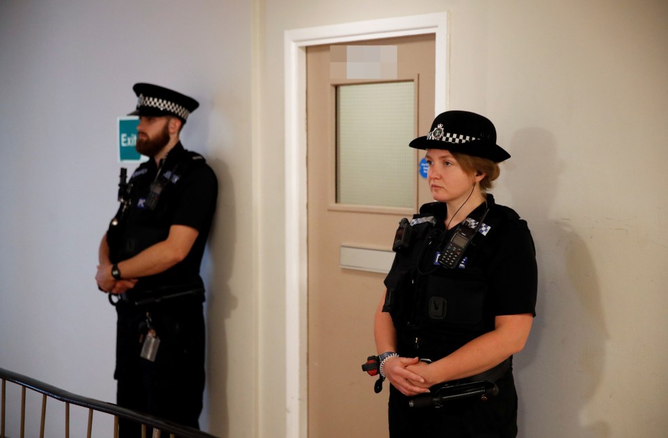 Police officers stand outside flats on Basingstoke Road where a suspect was apprehended last night