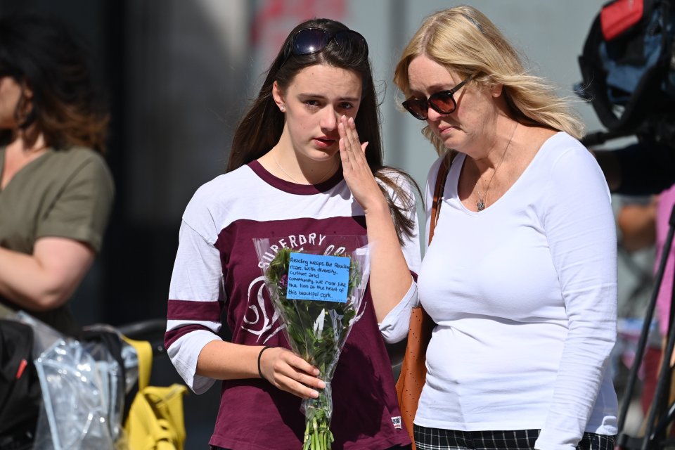 A woman wipes her face as they pay respects to those who lost their lives