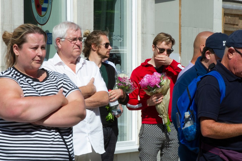 A man holds flowers as hundreds come out to remember the dead