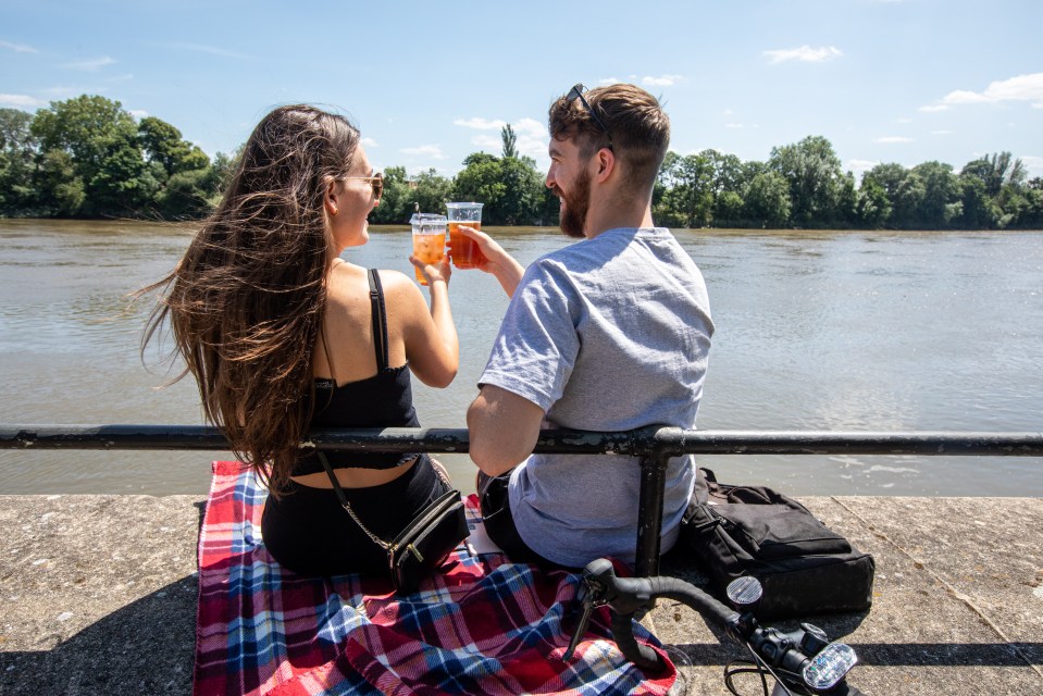 Pub goers Simon O’Brien and Megan Van Dessel enjoy a takeaway pint at the Black Lion Pub along the banks of the River Thames in Hammersmith