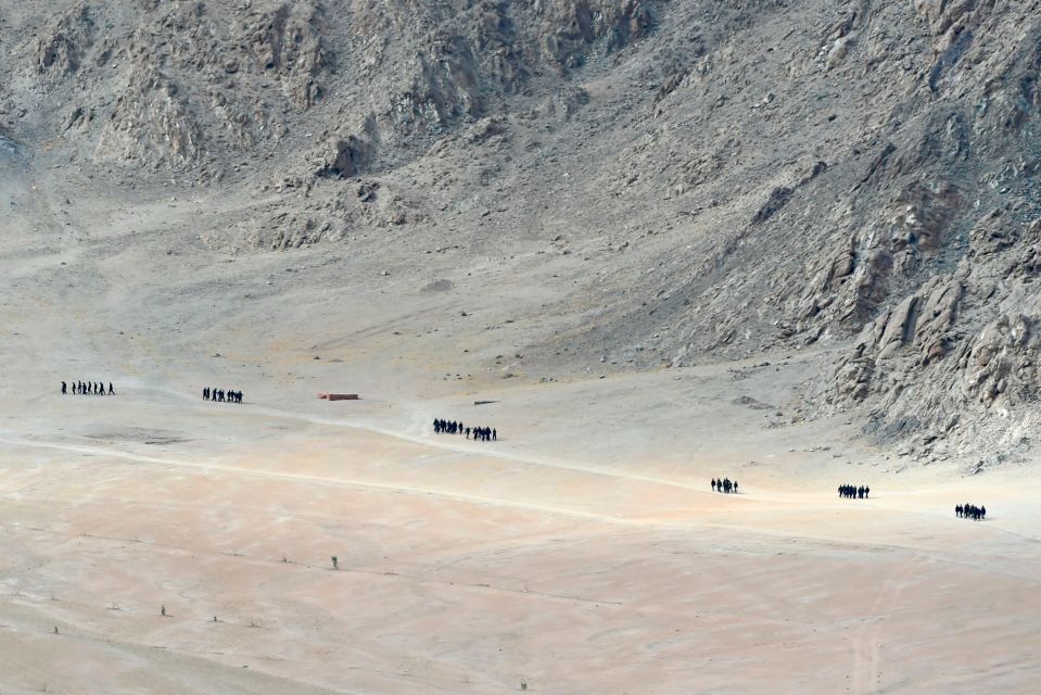 Indian soldiers walking near a mountain range in Leh