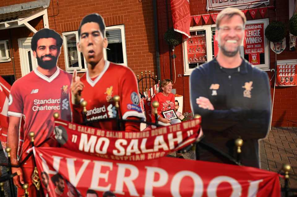 Liverpool fan Emily Farley sits outside her home, decorated with Liverpool banners and cut outs