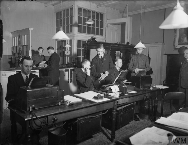 a black and white photo of men in an office with the letters iwm on the bottom