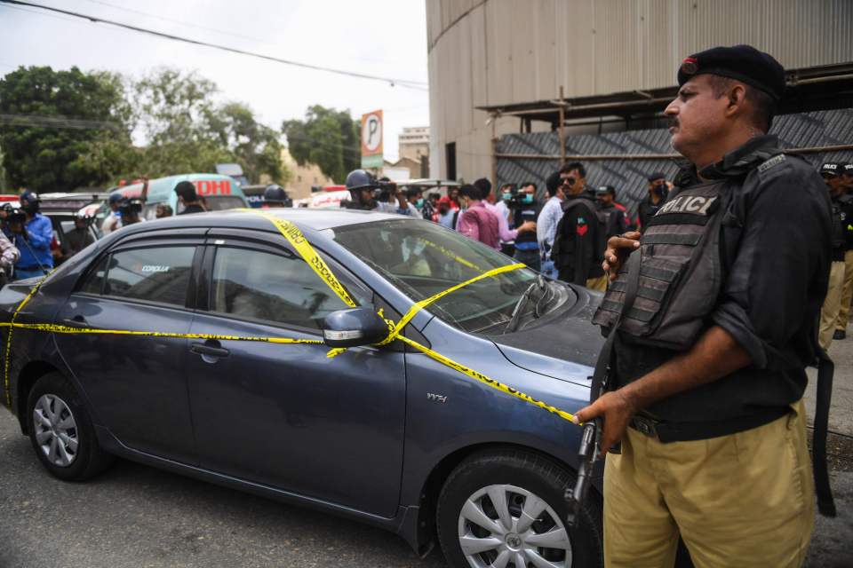 Security forces stand guard by the gunmen's car outside the stock exchange