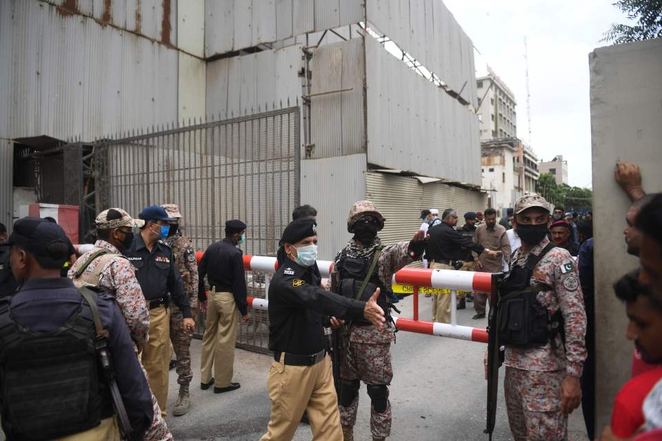 Security forces direct people outside the walls of the compound