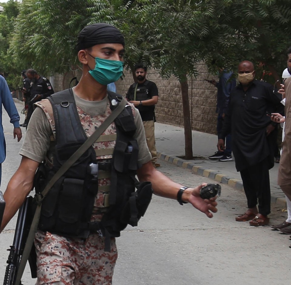 A security forces officer tentatively holds a grenade 