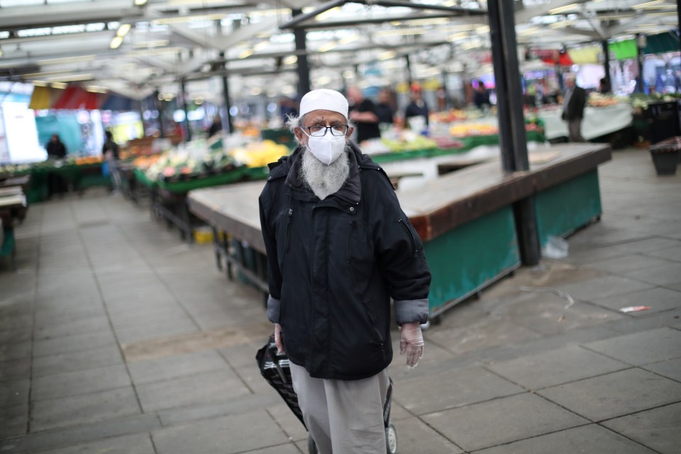 An elderly man wearing a mask as he walks through a market in Leicester 