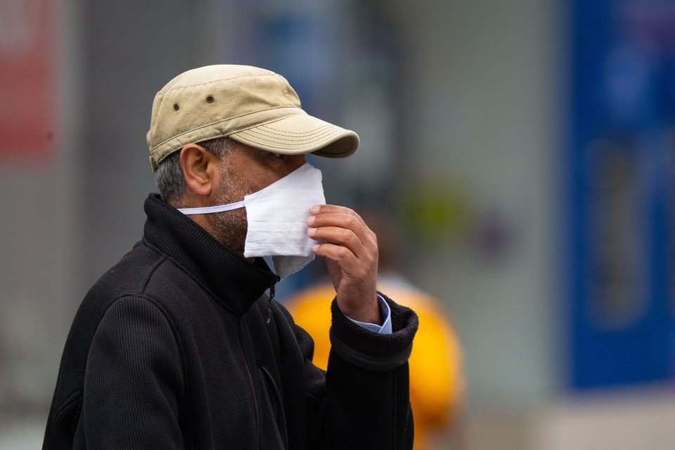 A man in Leicester holds a mask to his face after the city has seen a spike in cases