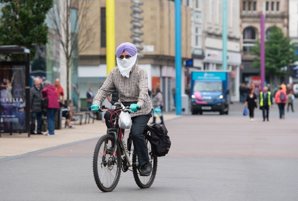 A Leicester local is seen cycling through the city centre with a face covering