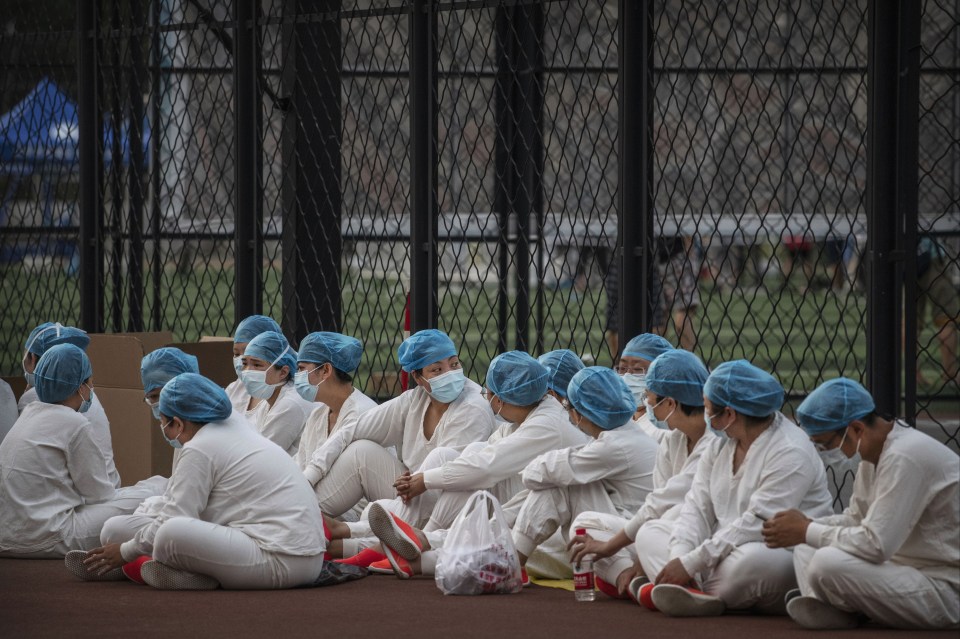 Chinese epidemic control workers wear protective suits and masks as they rest before resuming their duties 