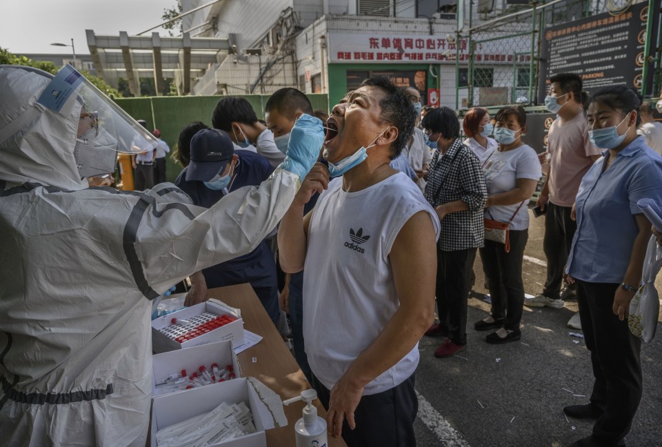 A Chinese epidemic control worker performs a nucleic acid test for COVID-19 on a man who has had contact with the Xinfadi Wholesale Market 