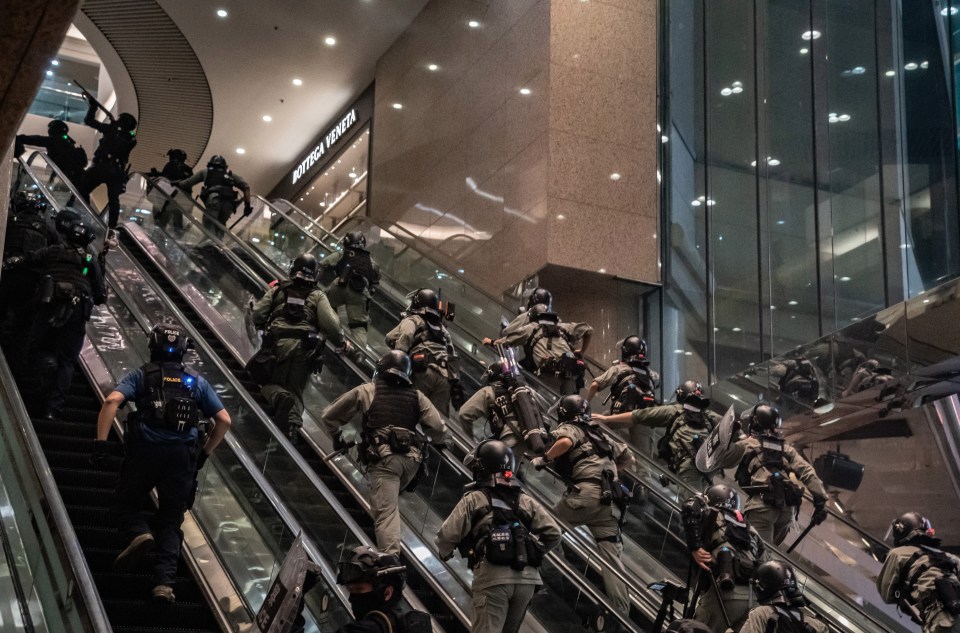 Riot police fire pepper balls at protesters as they storm the escalator in a Hong Kong mall