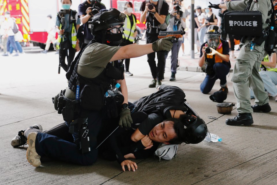 A cop raises his pepper spray handgun as he detains a man during a march