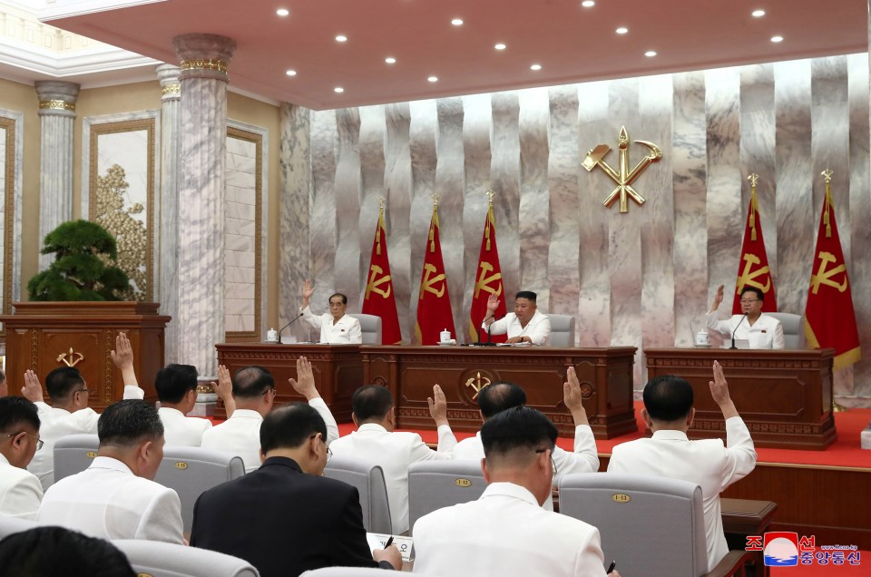 A pic said to be taken on the same day shows him addressing a roomful of officials, while sitting in front of party flags