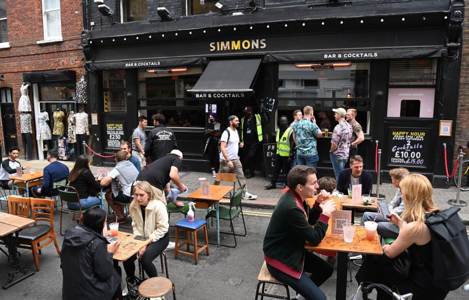 People drink outside a pub in Soho London on Saturday as pubs and restaurants reopened for business this weekend