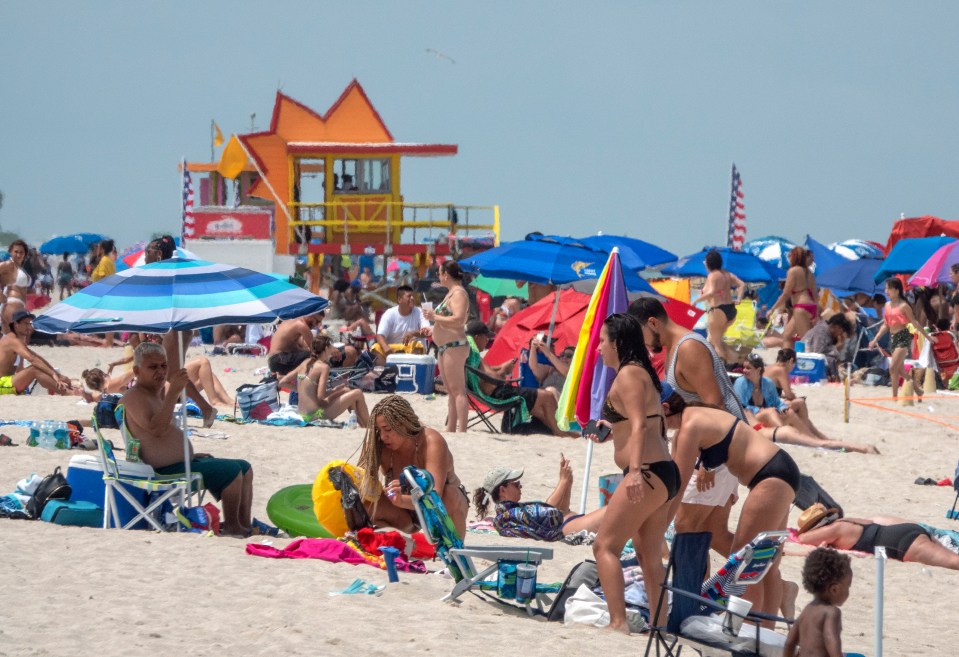 People enjoy a warm day at the beach in Miami Beach, Florida, July 12