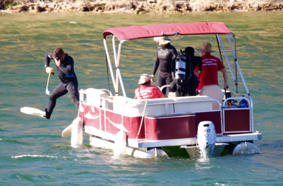 A diver searching the lake for Naya jumps into the water from a boat