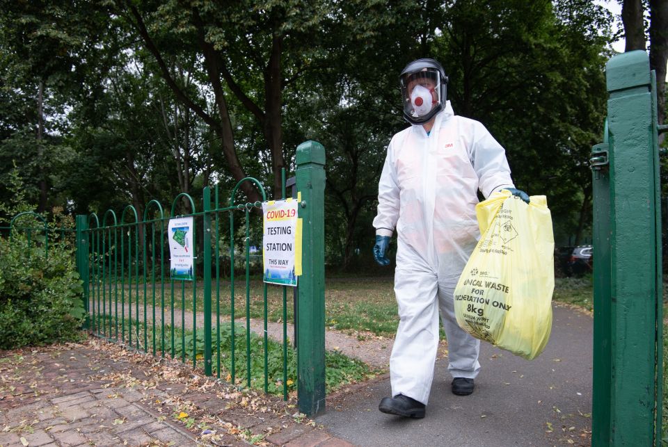 A worker for Leicester City Council carries a bag of clinical waste away from a Covid-19 testing station at Spinney Hill Park