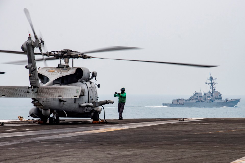 A MH-60R Sea Hawk lands as USS mustin sails in the background