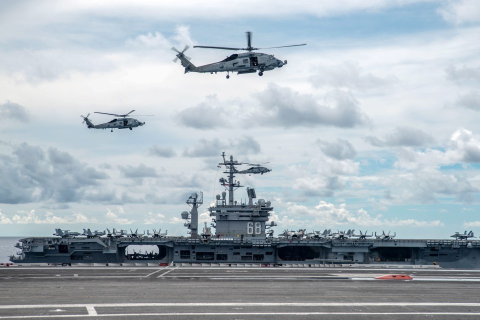 Two helicopters hover over the pair of US Navy carriers