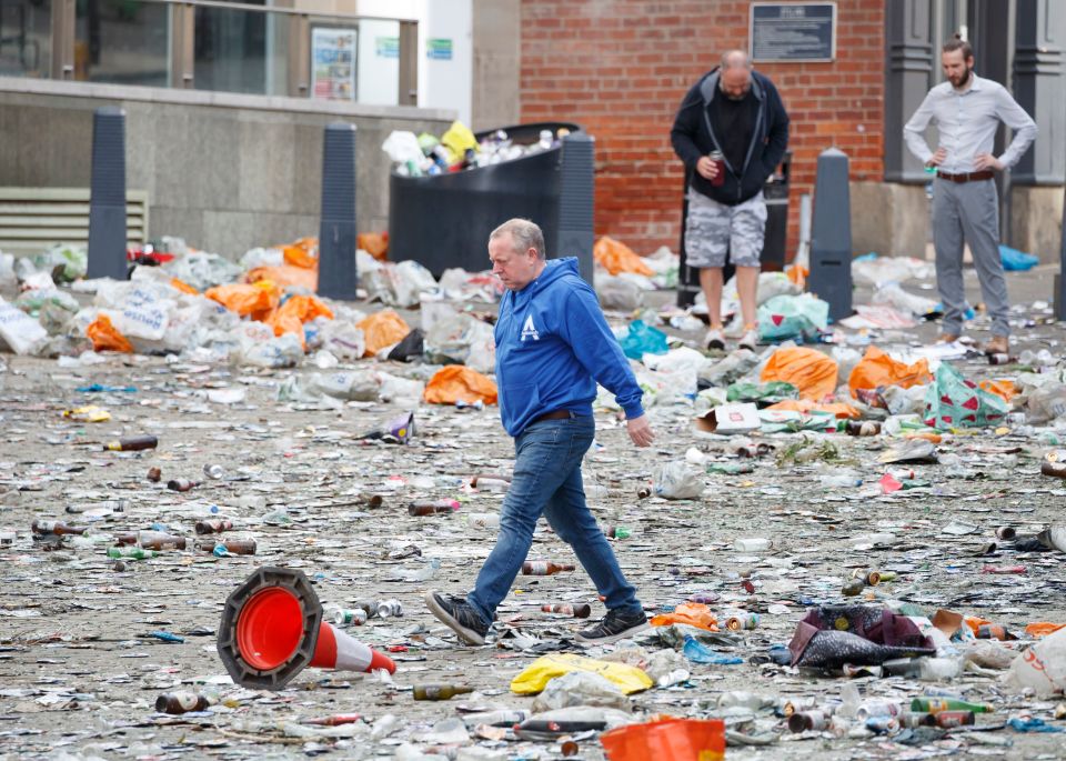 Members of the public walk through what looks like a war zone