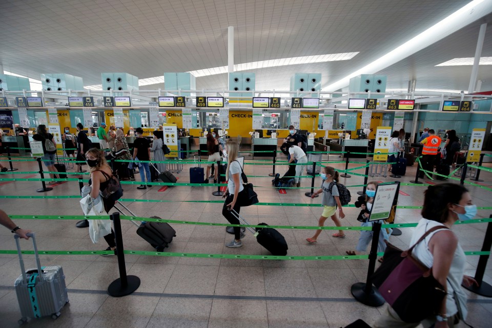 Passengers queue at a Vueling check-in desk at Josep Tarradellas Barcelona-El Prat airport