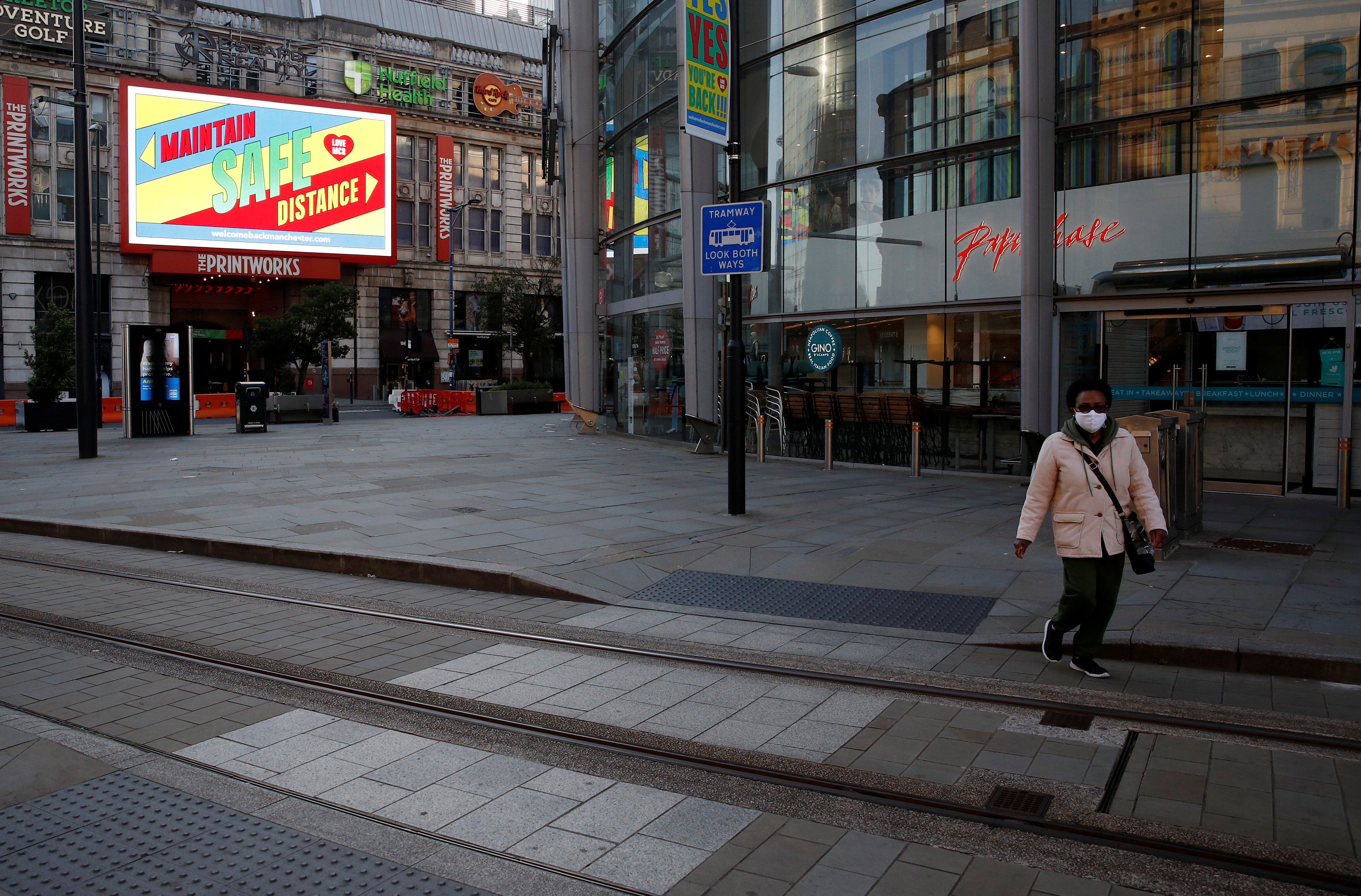 A woman wearing a face mask walks through Manchester