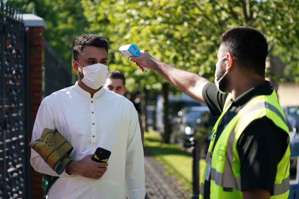 A man wearing a face mask has his temperature checked to try stop the spread of coronavirus, before being allowed to go into Manchester Central Mosque