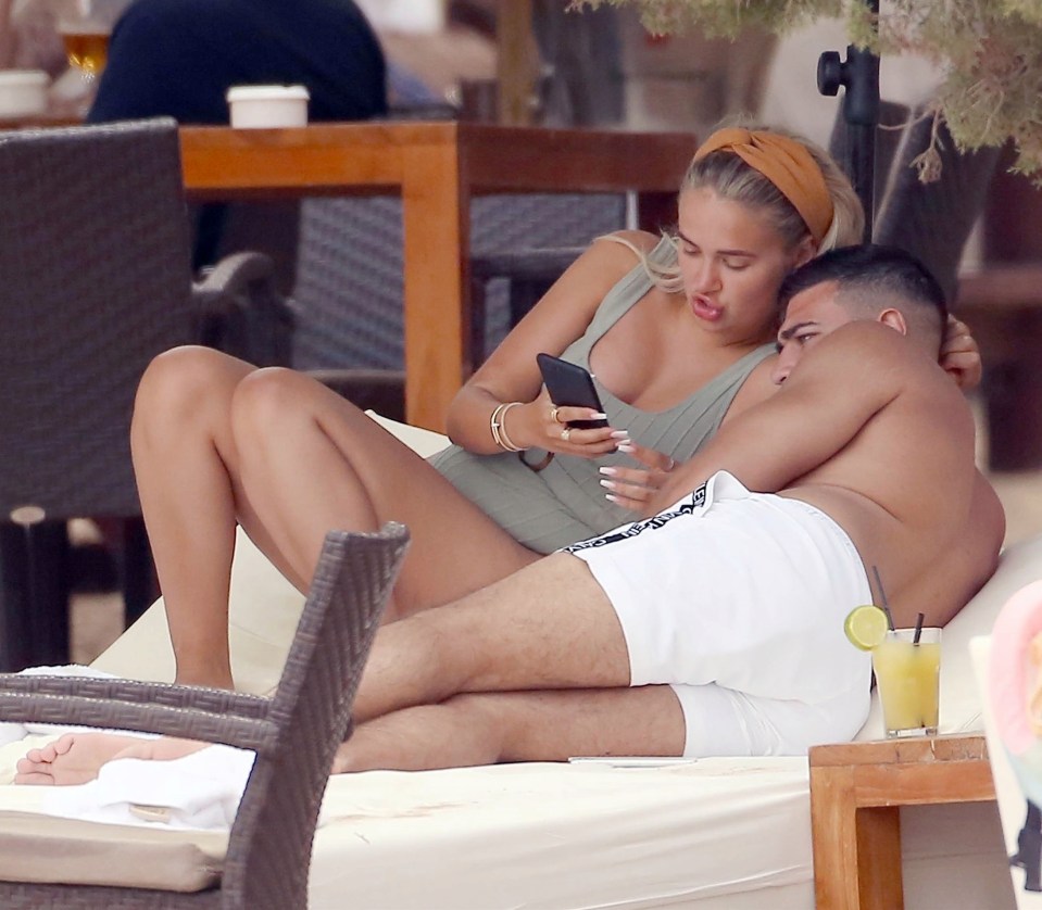 The tanned couple gazed at her phone at the luxurious Spanish resort