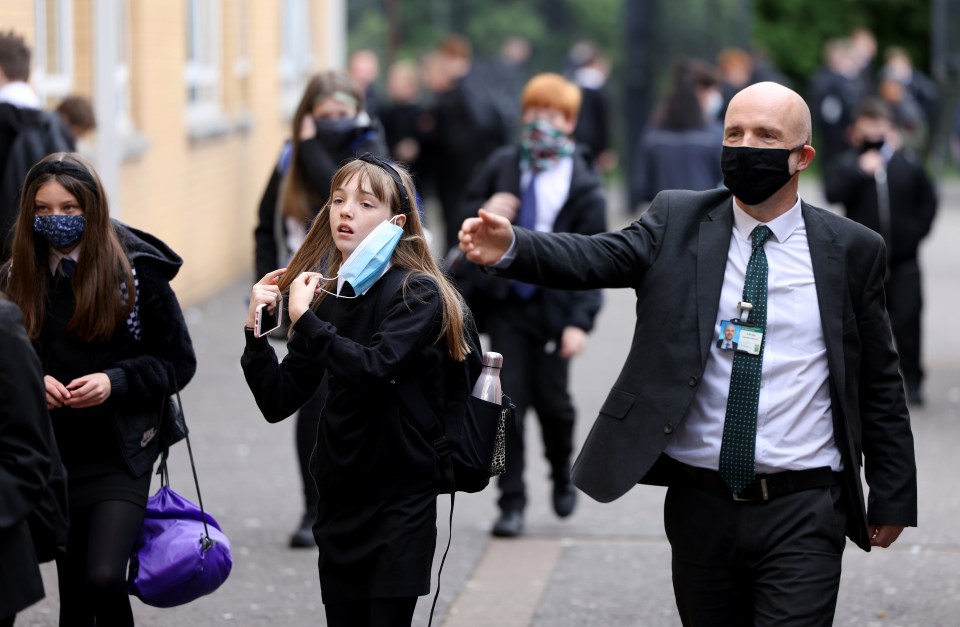 A girl fixes her masks before heading into school this morning