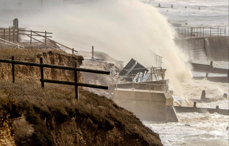 A beach hut is swallowed up from a cliftop by powerful waves battering the seafront walls at Milford on Sea, Hampshire