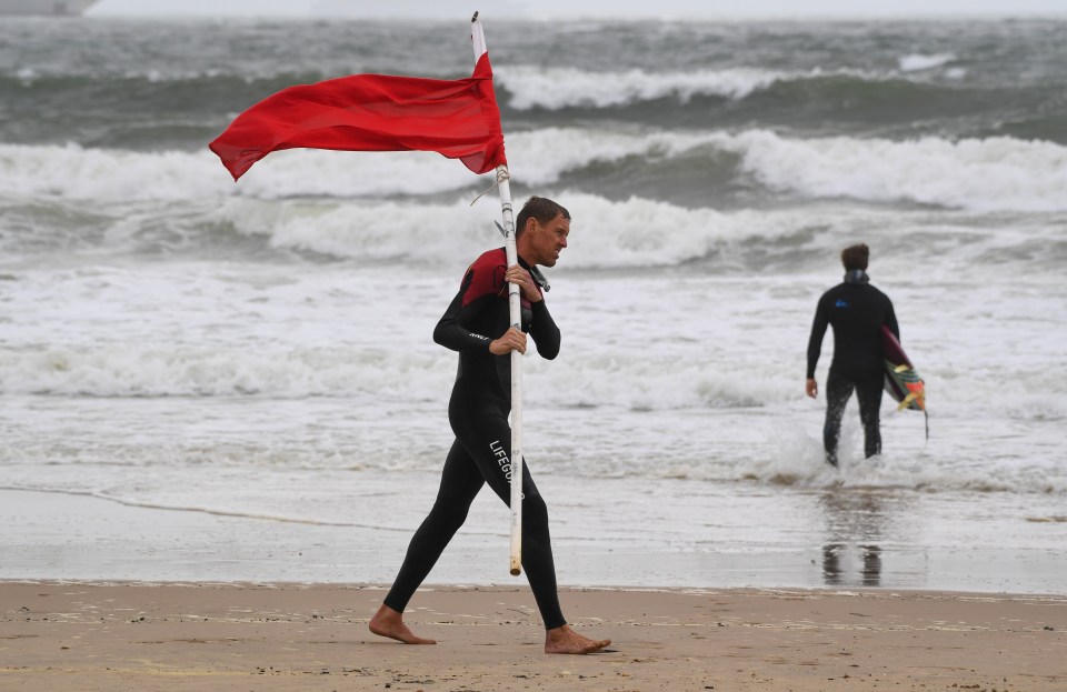 A lifeguard puts out a red warning flag at Bournemouth beach yesterday