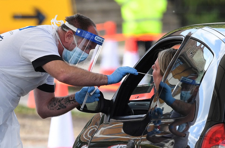 A medical worker takes a swab at a drive-in coronavirus testing facility