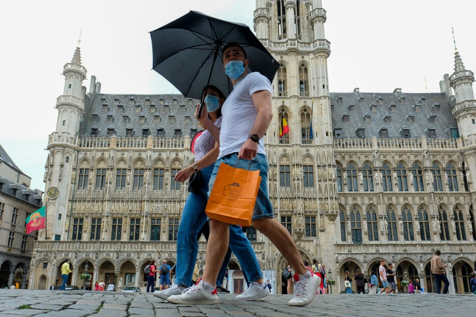 People wearing face masks walk in the centre of Brussels