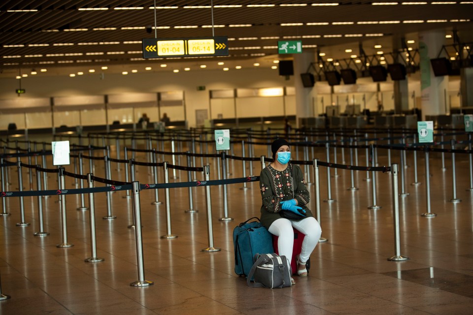 A passenger sits at the almost empty departures hall at the Zaventem international airport