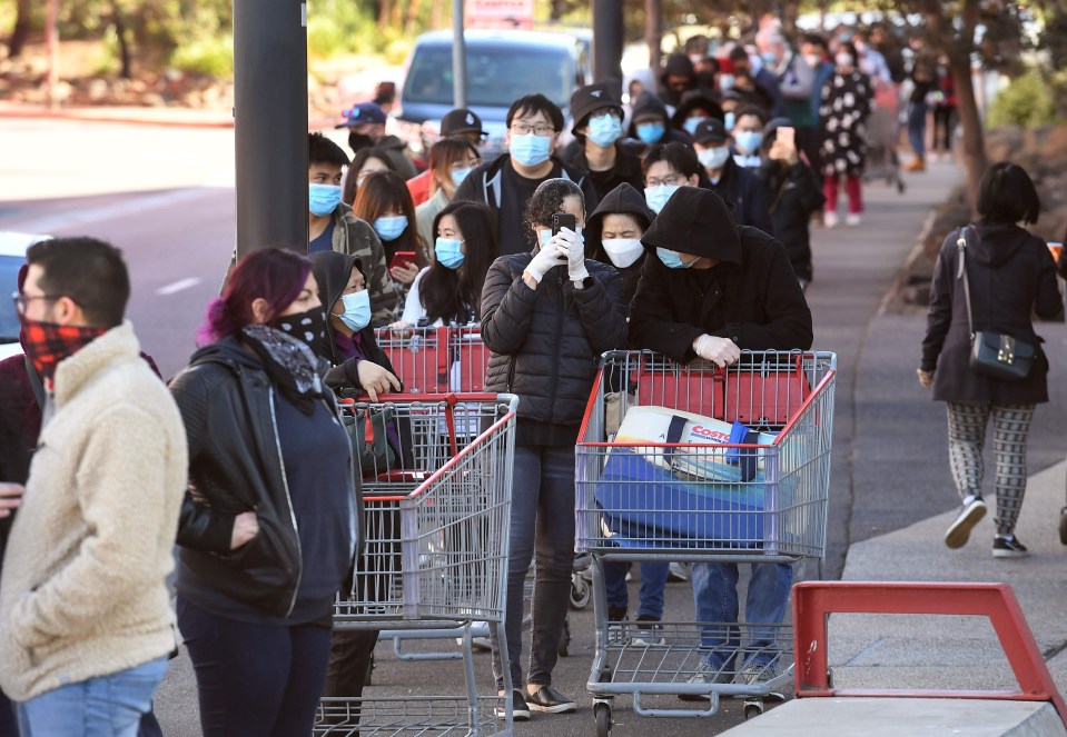 Masked shoppers wait in a huge queue outside a Melbourne supermarket yesterday