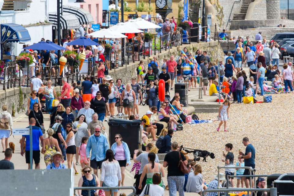 Holidaymakers and sunbathers flock to the beach at the seaside resort of Lyme Regis in Dorset on a day of warm sunny spells