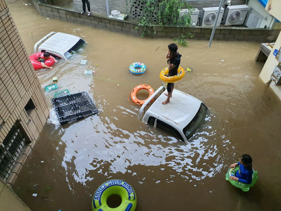 A stranded local waits to be rescued on the roof of a car in Hadong