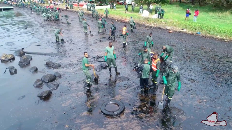 A still image taken from a drone video shows a cleanup crew working at the site of an oil spill 