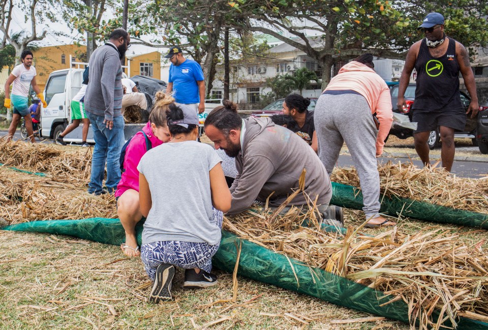 As oil continues to leak from the grounded ship, residents in Mauritius are in a race to mop up the mess, shoving straw into sacks to absorb the leaking fuel